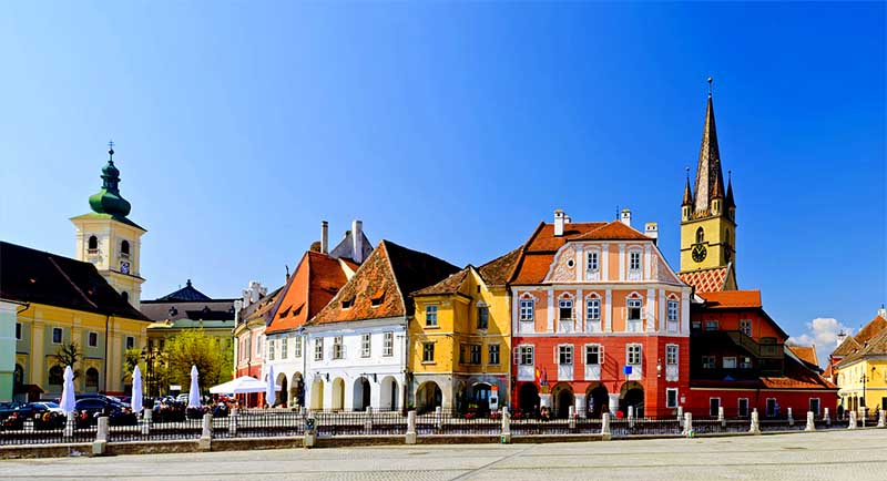 Sibiu – farebné historické domy na hlavnom námestí, veža kostola v pozadí
