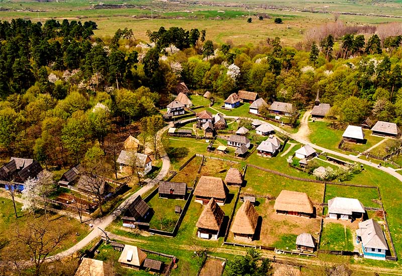 ASTRA Museum v Rumunsku, letecký pohľad na rozsiahly skanzen s historickými drevenými stavbami a dedinou v prírode