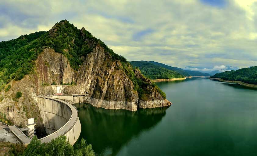 Priehrada Vidraru v rumunských Karpatoch, oblúková hrádza a horské jazero obklopené lesmi, panoramatický pohľad