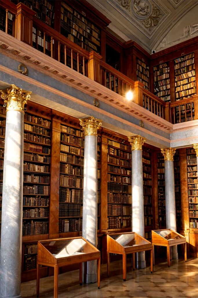 Knižnica v Pannonhalme, barokový interiér s vysokými regálmi, stĺpmi a vzácnymi knihami po stenách