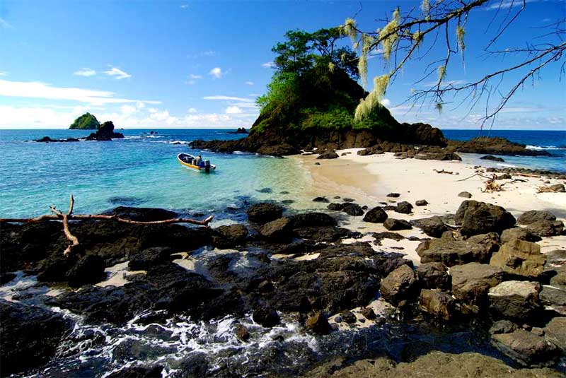 Skalnatá tropická pláž v provincii Chiriquí v Paname s tyrkysovým morom a malým člnom