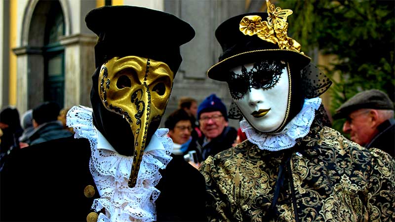 Dvojica účastníkov Benátskeho karnevalu v tradičných maskách a historických kostýmoch