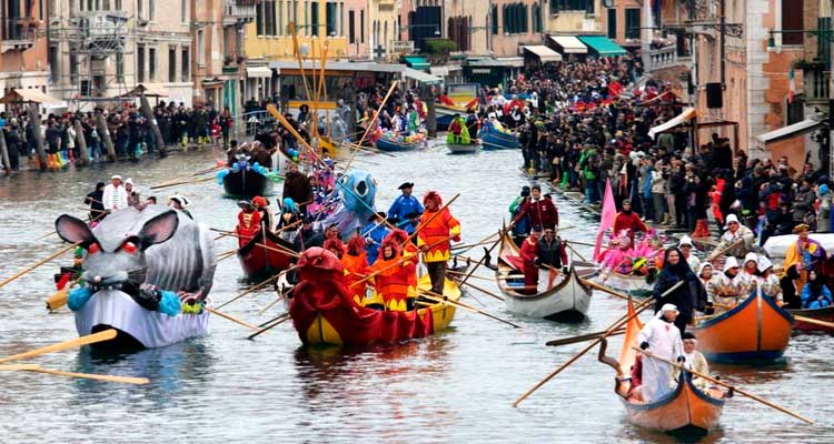 Lodný sprievod Benátskeho karnevalu na kanáli s maskami, kostýmami a zaplnenými brehmi