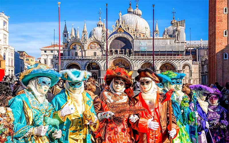 Benátsky karneval s účastníkmi v bohatých historických kostýmoch a maskách na Námestí svätého Marka v Benátkach