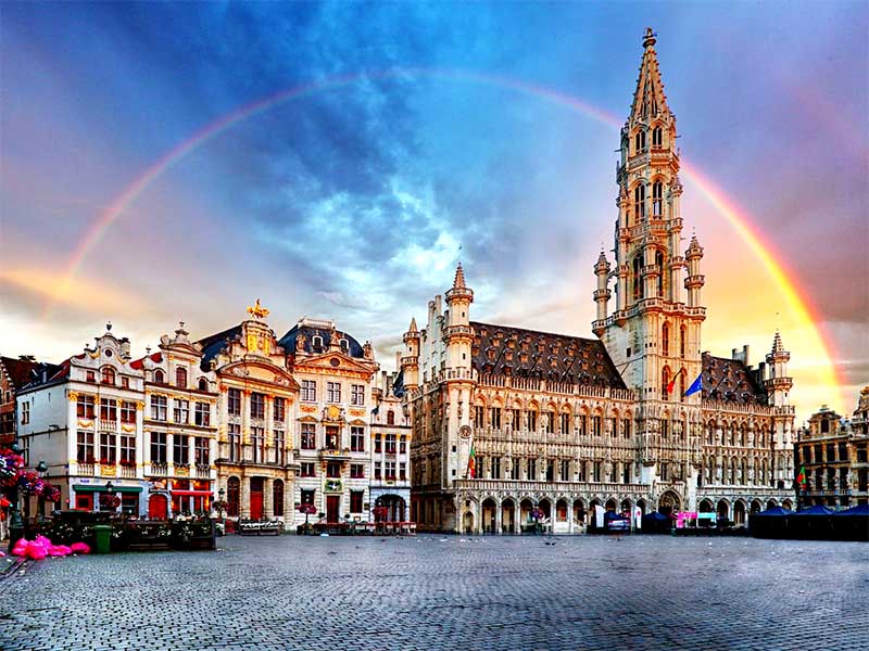 Historické námestie Grand Place v Bruseli s radnicou a dúhou na oblohe