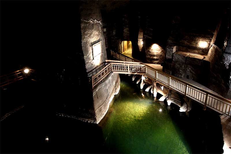 Podzemné jazero v Soľnej bani Wieliczka s dreveným mostíkom a zelenou slanou vodou